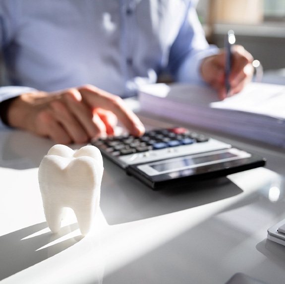 A large model tooth in front of a businessperson calculating a bill