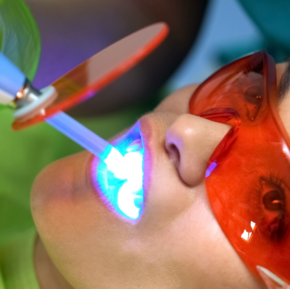 Woman receiving professional teeth whitening in dental chair