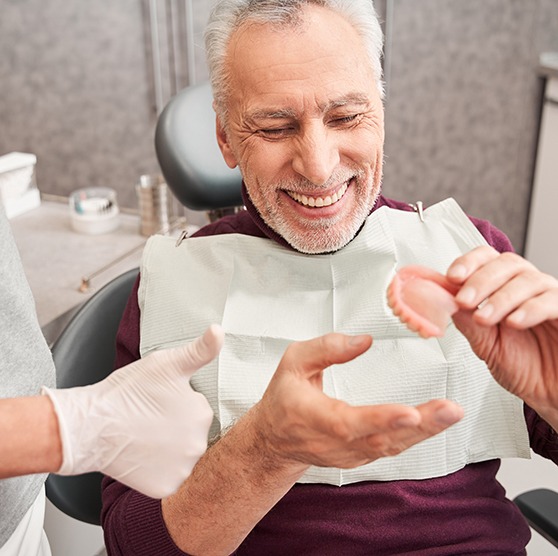 A dentist showing dentures to a male patient