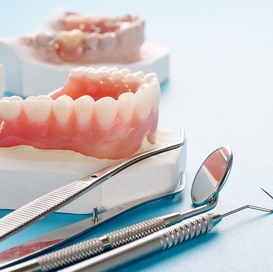A complete denture next to some dental tools