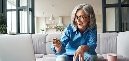 Patient in Putnam smiling in a mirror with dentures