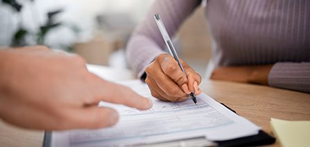 a hand pointing at a new patient form that someone is filling out