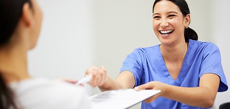 a front desk staff handing a patient forms
