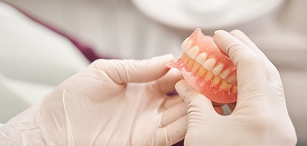 Dentist in Putnam holding dentures