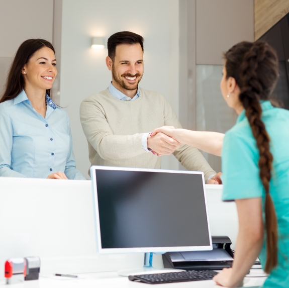 Man shaking hands with dental team member at front desk