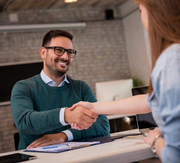 Man shaking hands with dental team member across desk