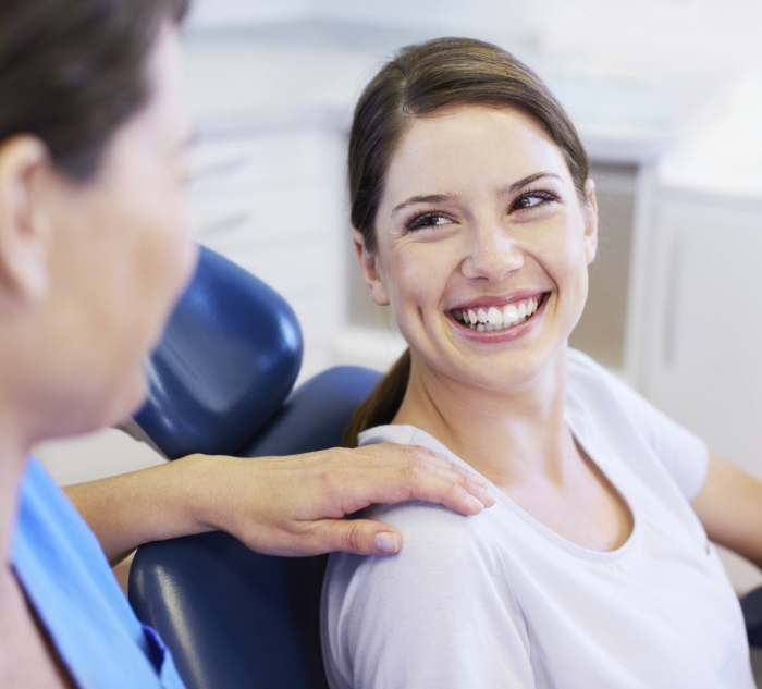 Woman in dental chair smiling at her dentist