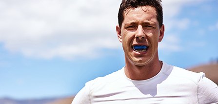 Man in white shirt wearing blue mouthguard