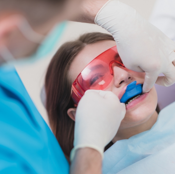 Young woman in dental chair having fluoride applied to her teeth