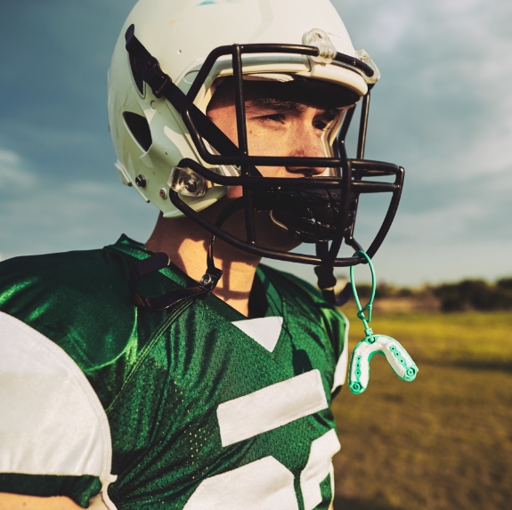 Football player with mouthguard hanging from his helmet