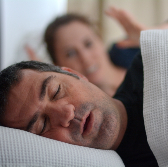 Woman awake in bed looking at snoring man next to her