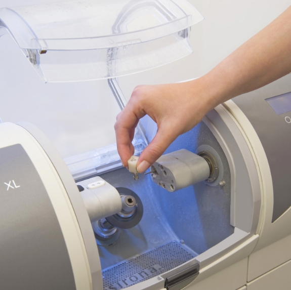 Dentist placing a small ceramic block into milling machine