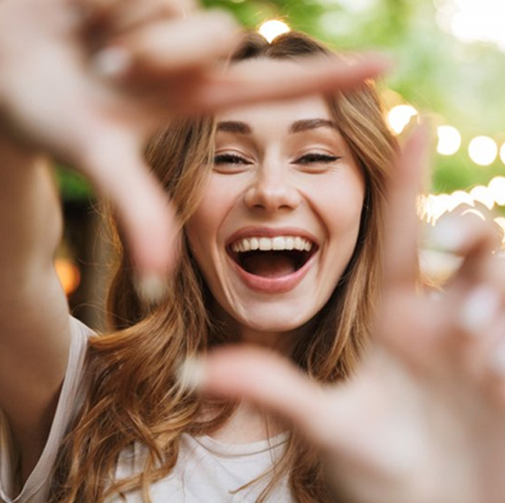 Woman outlining her smile by forming a square with her fingers